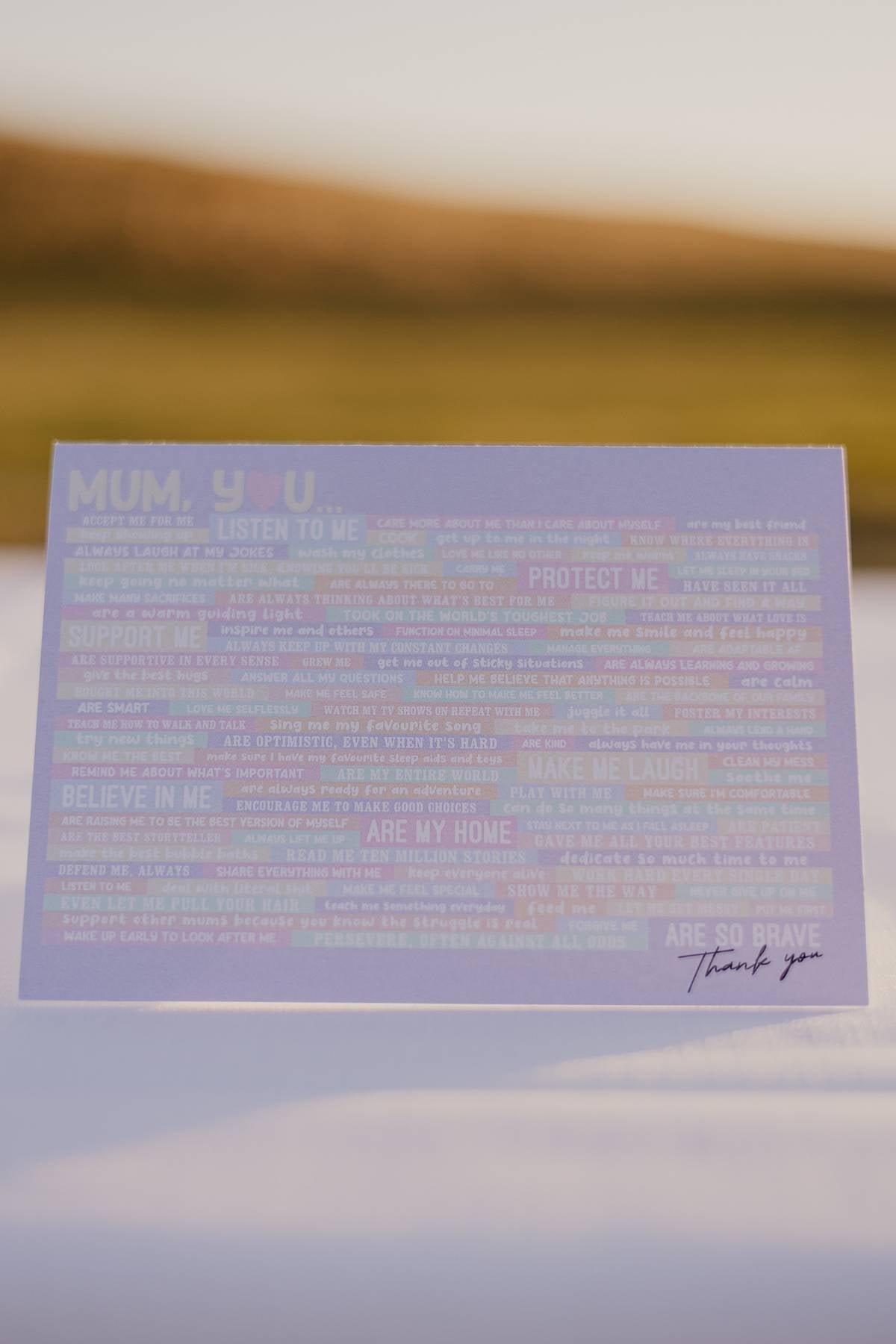 Front of the thank you Motherhood Milestones card. It has the words mum, you and then a long list of things that mothers do everyday that often gets overlooked. At the end it says thank you. The background of the card is purple and each word or phrase is highlighted in a different colour.