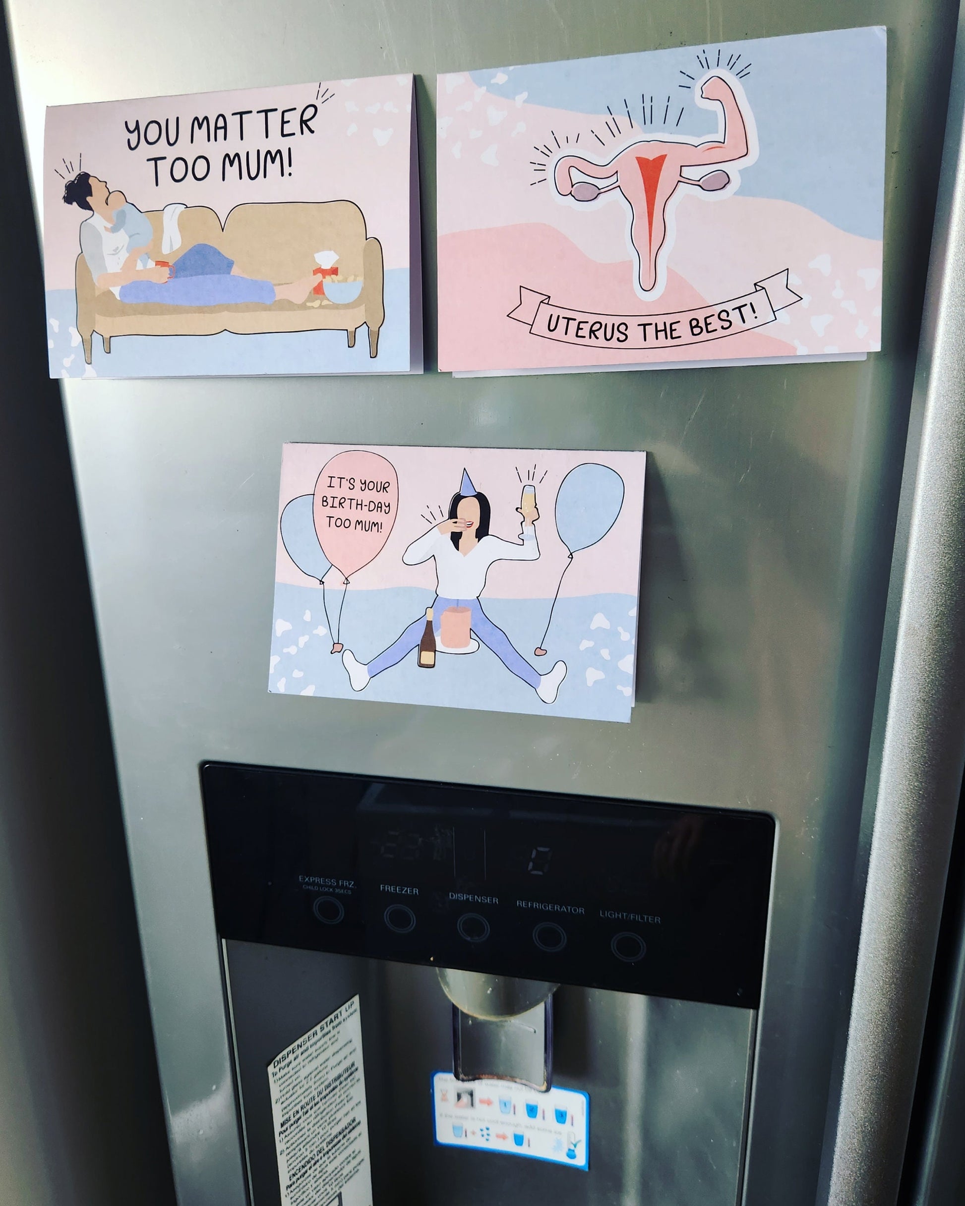 A picture of a fridge with three motherhood milestones cards sticking on it, it's your birthday too mum, uterus the best and you matter too mum.